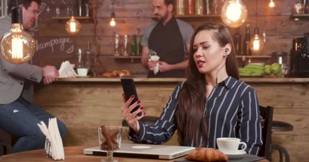 Jonge zakenvrouw die zich bezighouden met een video-oproep in een koffieshop - Video