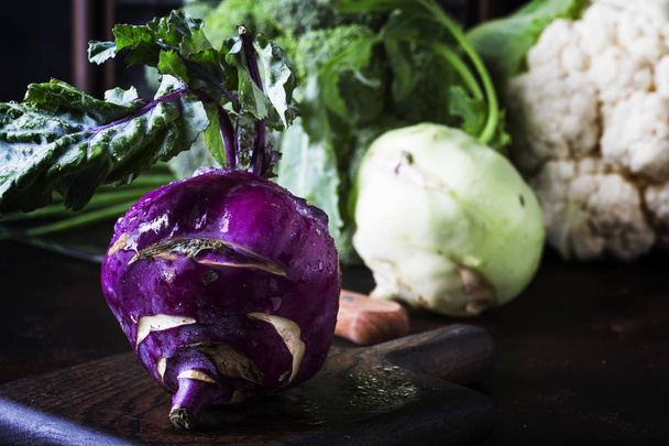 Purple organic fresh kohlrabi cabbage, summer harvest on brown kitchen table. selective focus - Foto, Imagem