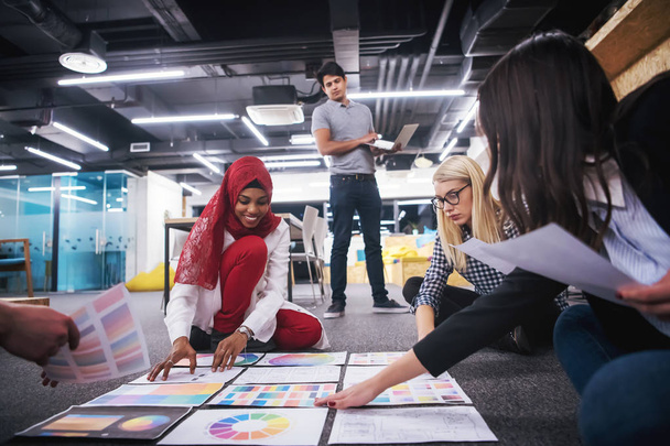 mladá černá muslimská podnikatelka, která se setkala se svým multietnickým startupním obchodním týmem v moderním kancelářském interiéru a představila nové nápady na podlaze - Fotografie, Obrázek