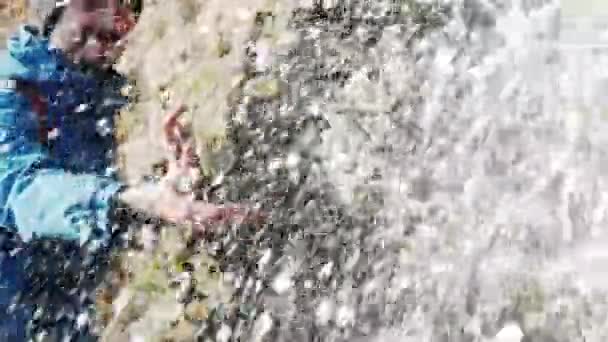 山の中の滝の近くの青いジャケットの若い男旅行者 - 映像、動画