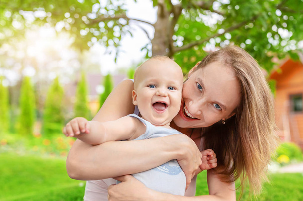 Hermosa madre con lindo bebé niño divirtiéndose al aire libre. Retrato de mamá con un niño divertido sonriendo en el verde jardín de verano. Familia feliz y paternidad. Cuidado de niños
. - Foto, imagen