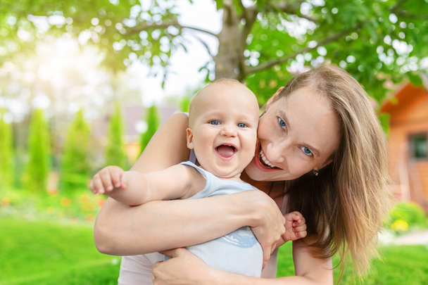 Kaunis äiti söpö pieni vauva poika hauskaa ulkona. Muotokuva äiti hauska lapsi hymyilee vihreä kesäpuutarha. Onnellinen perhe ja kasvatus. Lasten hoito
. - Valokuva, kuva