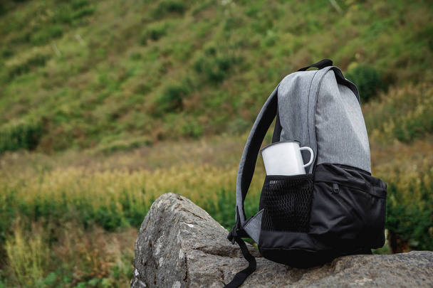 A backpack, a mug, a notepad and a map are lying on the grass. Tourist equipment. The apple lies in the pocket of the backpack. Walk in the forest. Camping in the mountains - Φωτογραφία, εικόνα