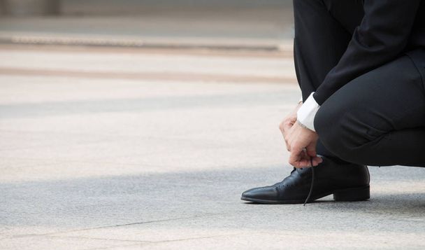 Close up of part of businessman who ready to run for the competition. He start his career and focus to his goal with confident.  Man is tying his shoelaces - Photo, Image