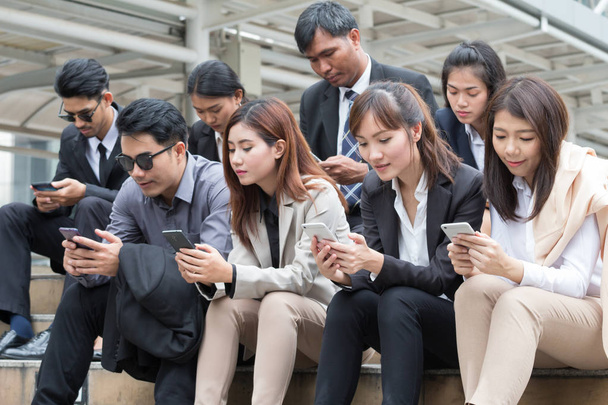 Grupo de empresários e mulheres de negócios se concentrar em seus smartphones. Eles estão verificando as notícias, e-mail, índice de ações e seu trabalho. - Foto, Imagem