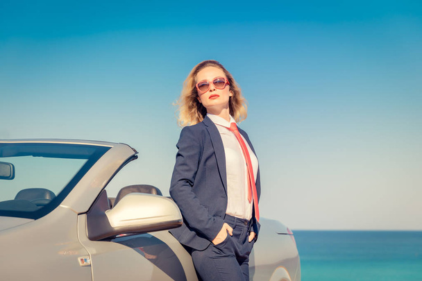 Successful young businesswoman on the beach. Woman sitting on the cabriolet classic car. Summer vacations and freedom travel concept - Foto, immagini