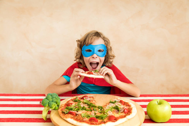 Superhero child eating superfood. Happy kid having lunch at home. Healthy eating and lifestyle concept. Green vegetarian food - Фото, изображение