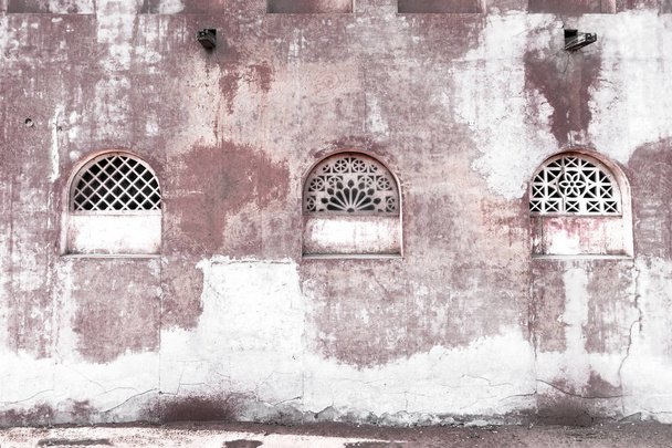 Παλιό τείχος της Ανατολικής αρχιτεκτονικής με ένα μοτίβο σχάρες στα παράθυρα. Τέχνη - Φωτογραφία, εικόνα
