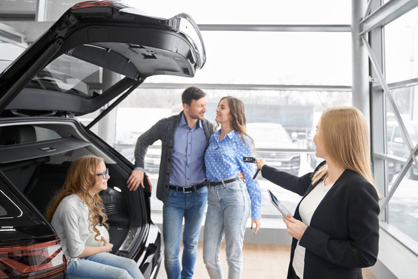 Female car dealer giving to buyers car keys. - Фото, зображення
