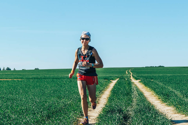 May 26-27, 2018 - Naliboki, Belarus: All-Belarusian amateur marathon Naliboki, woman running on rural road in field during race - Foto, Imagen