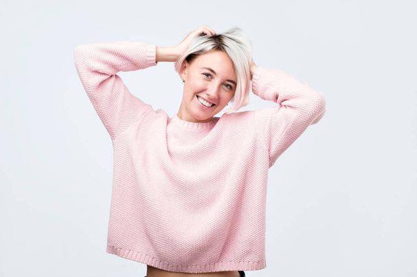 Festett haj nő öltözve rózsaszín pulóver, keresi az elégedettség a kamerát, hogy boldog. - Fotó, kép