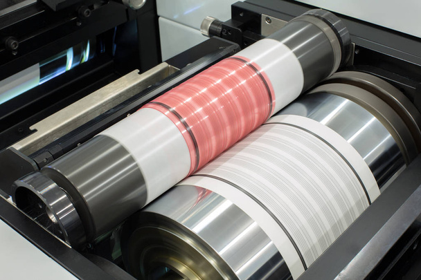 Flexography printing process on in-line press machine. Photopolymer plate stuck on printing cylinder, substrate is sandwiched between the plate and the impression cylinder to transfer the ink. - Photo, Image