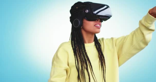 Multi ethnic lady with dreadlocks using a virtual reality glasses to pick a program to using virtual she type with finger , very enthusiastic in a studio with a blue background wall - Πλάνα, βίντεο