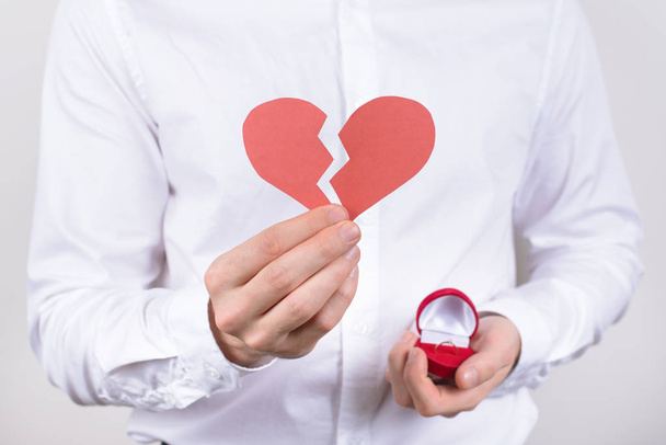 No date concept. Cropped closeup photo of confused unhappy sad guy holding showing broken heart in hand isolated grey background - Photo, Image