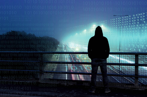 Un concepto cibernético de números sobre capas en la parte superior de una figura solitaria con capucha mirando el tráfico desde un puente por la noche
. - Foto, imagen