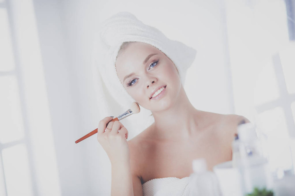 浴室に顔の粉を塗る若い女性の写真 - 写真・画像