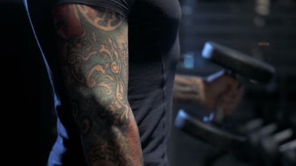 Guy flexing arms with dumbbells in his hands, gym workout, slow motion - Filmagem, Vídeo