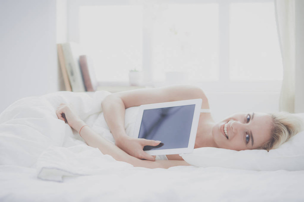 Girl holding digital tablet with blank screen and smiling at camera in bedroom - Φωτογραφία, εικόνα