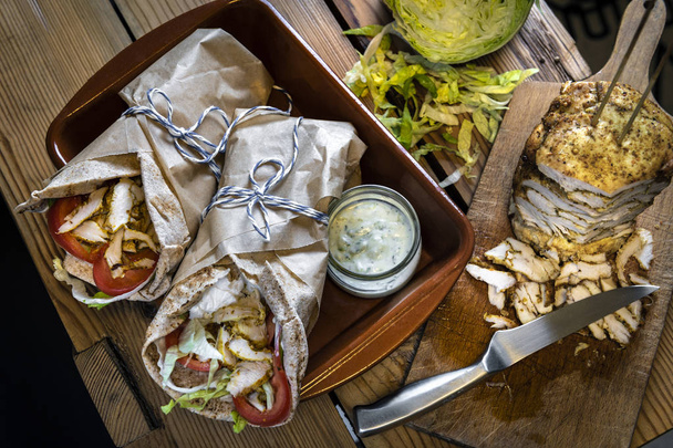 hausgemachte Dönerspieße mit Hühnerfleisch in gerösteten Tortilla-Wraps auf Holztisch - Foto, Bild