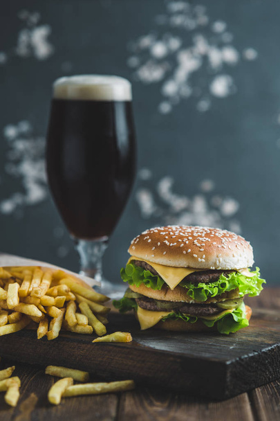 Burger aux pommes de terre et bière brune sur un plateau en bois sur fond bleu-gris
 - Photo, image