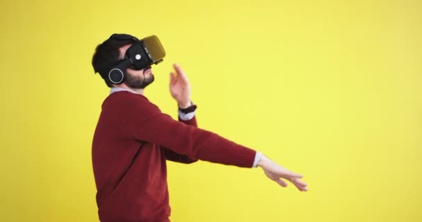 Funny man with a virtual reality glasses dacing charismatic in the studio with a yellow background wall, he are very excited - Imágenes, Vídeo