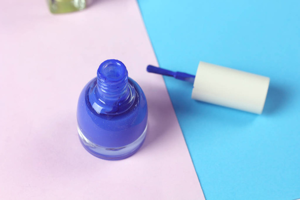blaue Nagellackflasche und Nagelbürsten auf rosa Hintergrund. Nagelpflege  - Foto, Bild