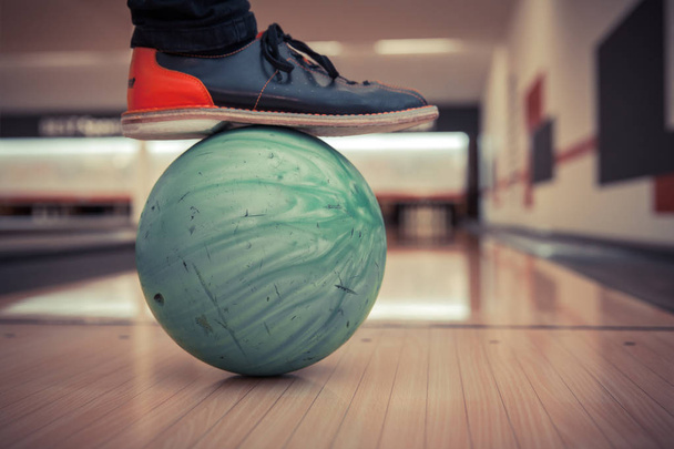 Bowlingbälle im Sportzentrum bereit zum Kegeln. Fuß im Schuh steht auf dem Ball - Foto, Bild