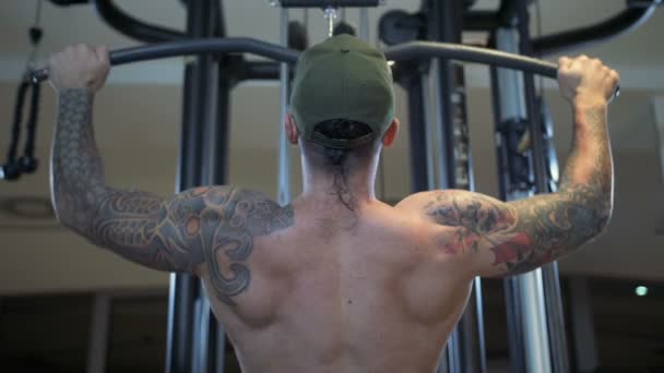 Mann im Fitnessstudio trainiert den Latissimus dorsi an der Latzugmaschine - Filmmaterial, Video