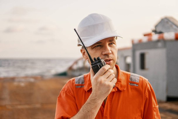 Oficial de convés no convés da embarcação offshore detém rádio walkie-talkie VHF
 - Foto, Imagem