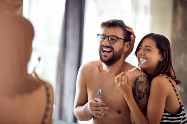 Happy couple brushing their teeth in the morning at home in bath - Φωτογραφία, εικόνα