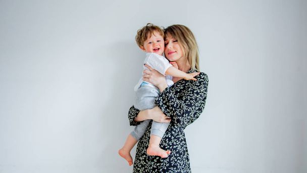 Mother and son on a white wall background at home - Фото, изображение