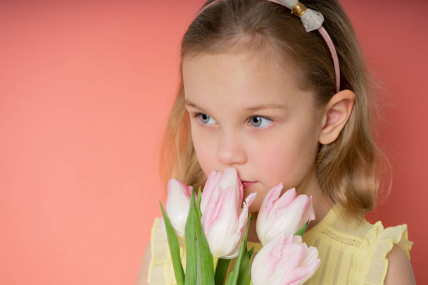 Retrato de una hermosa joven en vestido con un gran ramo de tulipanes aislados sobre fondo rosa
 - Foto, Imagen