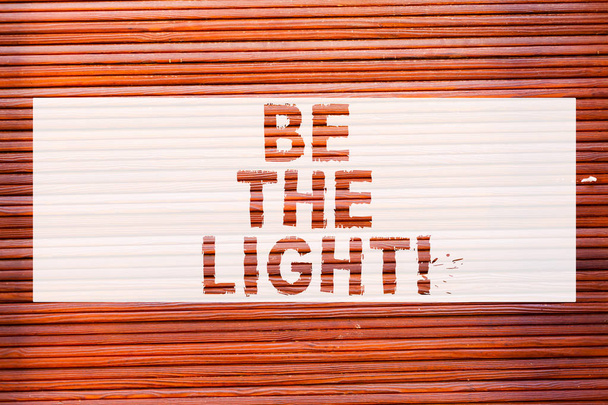 Escribiendo nota mostrando Be The Light. Exhibición de la foto del negocio Ilumine otra demostración con su actitud sea arte optimista de la pared del ladrillo como llamada motivacional del graffiti escrita en la pared
. - Foto, imagen