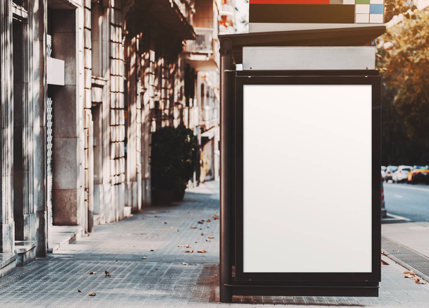 ein plakatierter Platzhalter innerhalb einer städtischen Bushaltestelle in der Nähe der Straße; vertikale, leere Werbebanner-Attrappe auf dem Pflasterstein; weiße, leere Informationstafel innerhalb einer Haltestelle des öffentlichen Verkehrs in Spanien - Foto, Bild