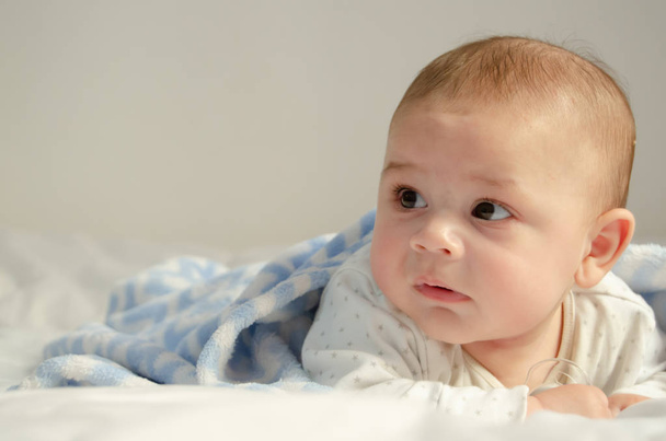 Ładna 4 miesiące chłopca o czas brzuch na biały kołdra pokryta niebieski koc - zdrowie i szczęśliwe dzieciństwo koncepcja - Zdjęcie, obraz