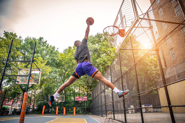 Afro-american basketball player training on a court in New York - Sportive man playing basket outdoors - Фото, изображение