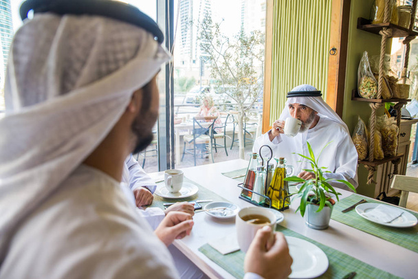 Group of middle eastern men wearing kandora bonding in a cafe' restarant in Dubai - Фото, изображение