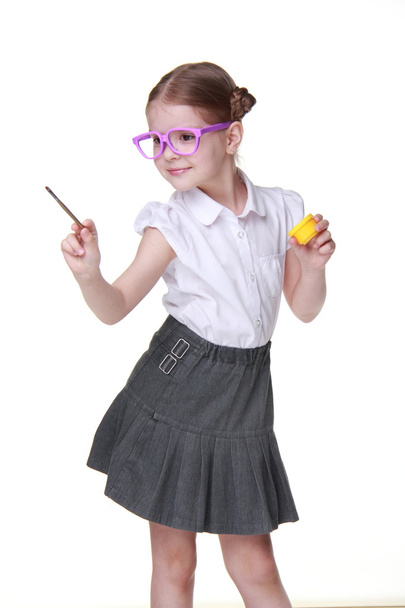 Studio image of schoolgirl with funny glasses posing with yellow paint and brush - Fotoğraf, Görsel