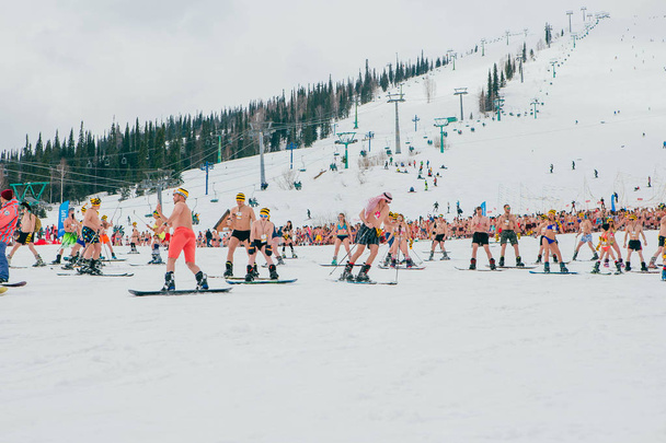 Sheregesh, Kemerovo region, Russia - April 14, 2018: Grelka Fest is a sports and entertainment activity for ski and snowboard riders in bikini. Crowd of people riding snowboard and mountain ski - 写真・画像