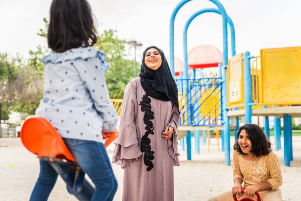 Happy arabian family having fun in Dubai - Mom together with her daughters in park play area - Fotó, kép