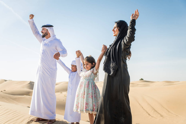 Arabian family with kids having fun in the desert - Parents and children celebrating holiday in the Dubai desrt - Fotó, kép