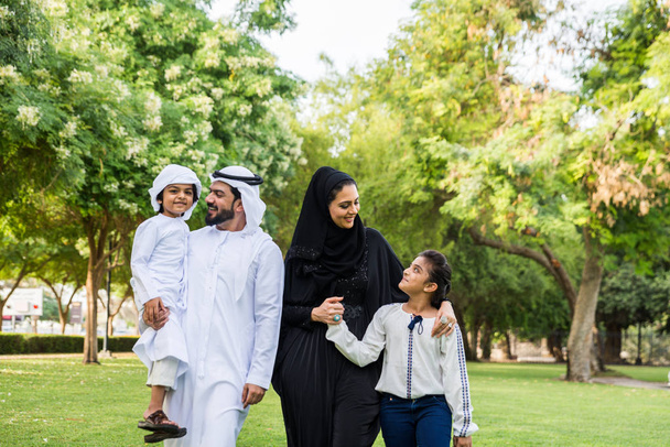 Happy middle-eastern family having fun in a park in Dubai - Parents and kids celebrating the weekend in the nature - Foto, afbeelding