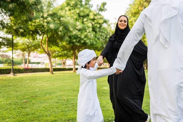 Happy middle-eastern family having fun in a park in Dubai - Parents and kids celebrating the weekend in the nature - Фото, изображение