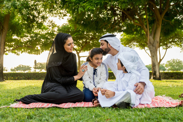 Happy middle-eastern family having fun in a park in Dubai - Parents and kids celebrating the weekend in the nature - Фото, зображення