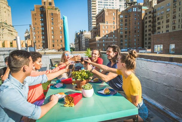 Young happy people having a barbecue dinner on a rooftop in New York - Group of friends having party and having fun - Foto, Imagem