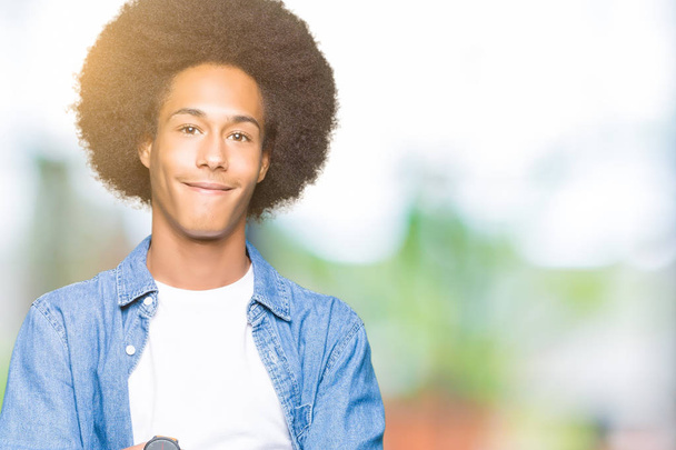 Молодой африканский американец с афро-волосами счастливое лицо улыбается со скрещенными руками, глядя в камеру. Позитивный человек
. - Фото, изображение