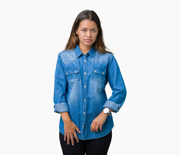 Young beautiful brunette woman wearing blue denim shirt over isolated background skeptic and nervous, frowning upset because of problem. Negative person. - Photo, Image