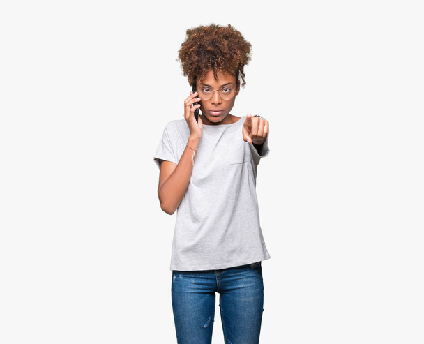 Młody african american kobieta rozmawia na smartfon na białym tle wskazując palcem do aparatu i do Ciebie, ręcznie zarejestrować, gest pozytywny i pewnie z przodu - Zdjęcie, obraz