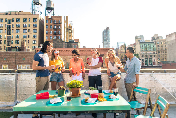 Young happy people having a barbecue dinner on a rooftop in New York - Group of friends having party and having fun - Foto, Bild