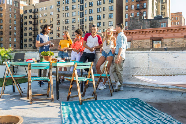 Young happy people having a barbecue dinner on a rooftop in New York - Group of friends having party and having fun - Zdjęcie, obraz